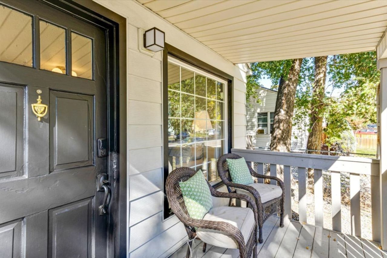 A porch with wicker chairs and a black door.
