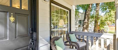 A porch with wicker chairs and a black door.