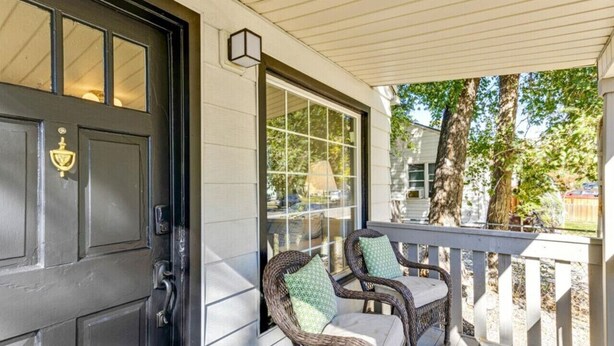 A porch with wicker chairs and a black door. - The Mountainside Cottage | Backyard | BBQ (Provo)