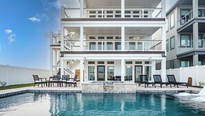 A multi-story residential building with a swimming pool, outdoor seating, and a white exterior. - The Sanctuary by Silver Sands Vacation Rentals (Port Aransas)