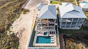 A large, multi-story beachfront property with a swimming pool and outdoor seating. - The Sanctuary by Silver Sands Vacation Rentals (Port Aransas)