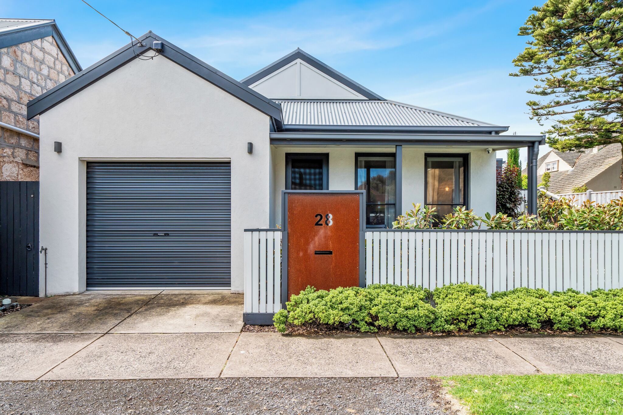Une maison moderne à deux étages, dotée d’un garage, d’une porte d’entrée portant le numéro « 28 » et d’un petit porche.