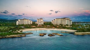 Ein Resort mit mehreren Hochhäusern, einem Strand und einem Wasserfall-artigen Felsformation.