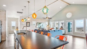 A spacious kitchen with a large island, bright pendant lights, and a view to the living area. - Beach-A-Holic by Silver Sands Vacation Rentals (Port Aransas)
