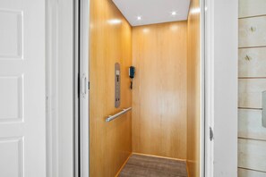 A wooden elevator with a metal handrail and a control panel. - Beach-A-Holic by Silver Sands Vacation Rentals (Port Aransas)