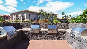 An outdoor barbecue area with stone walls and three grills.