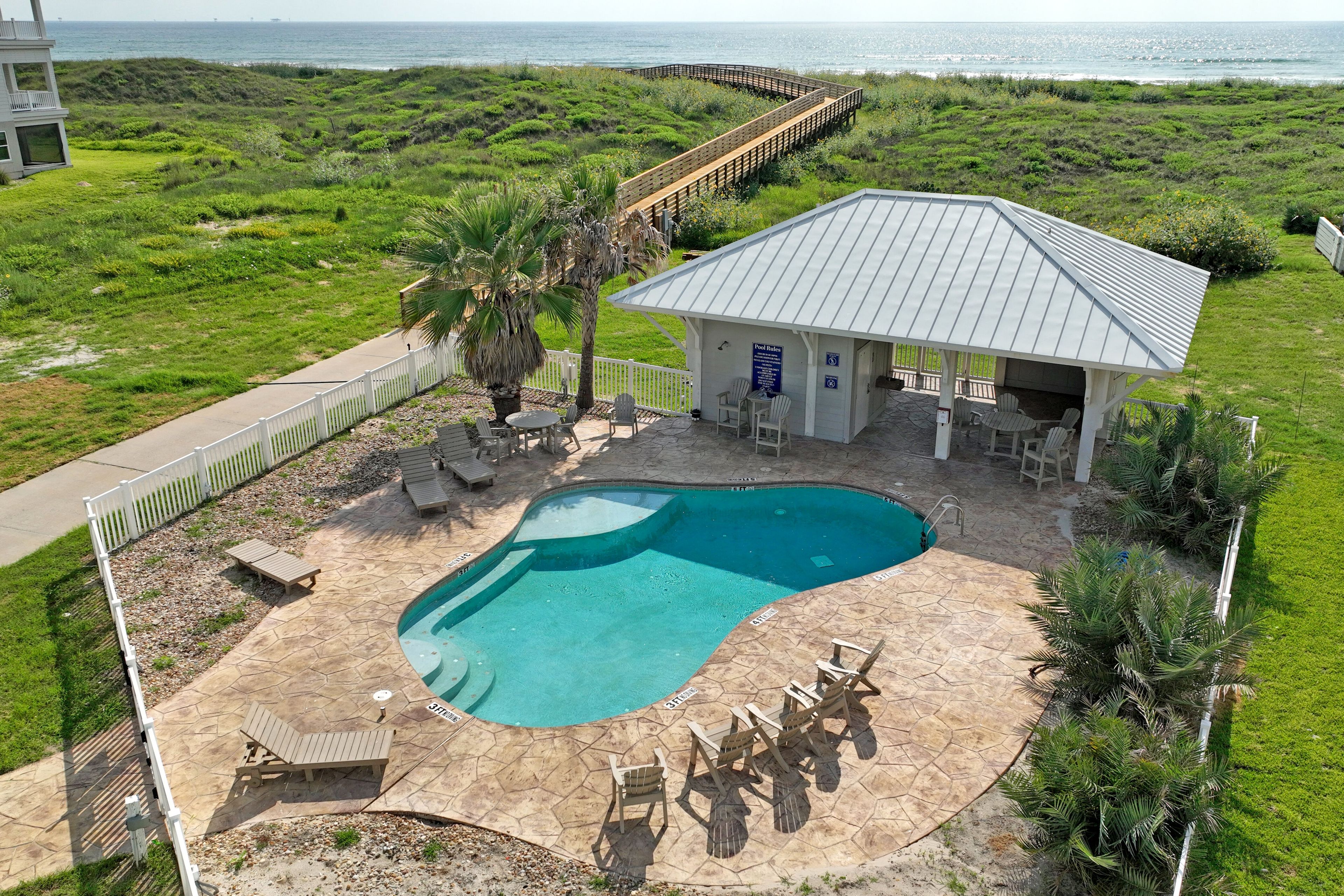 A pool area with a curved pool, lounge chairs, and a covered seating area.