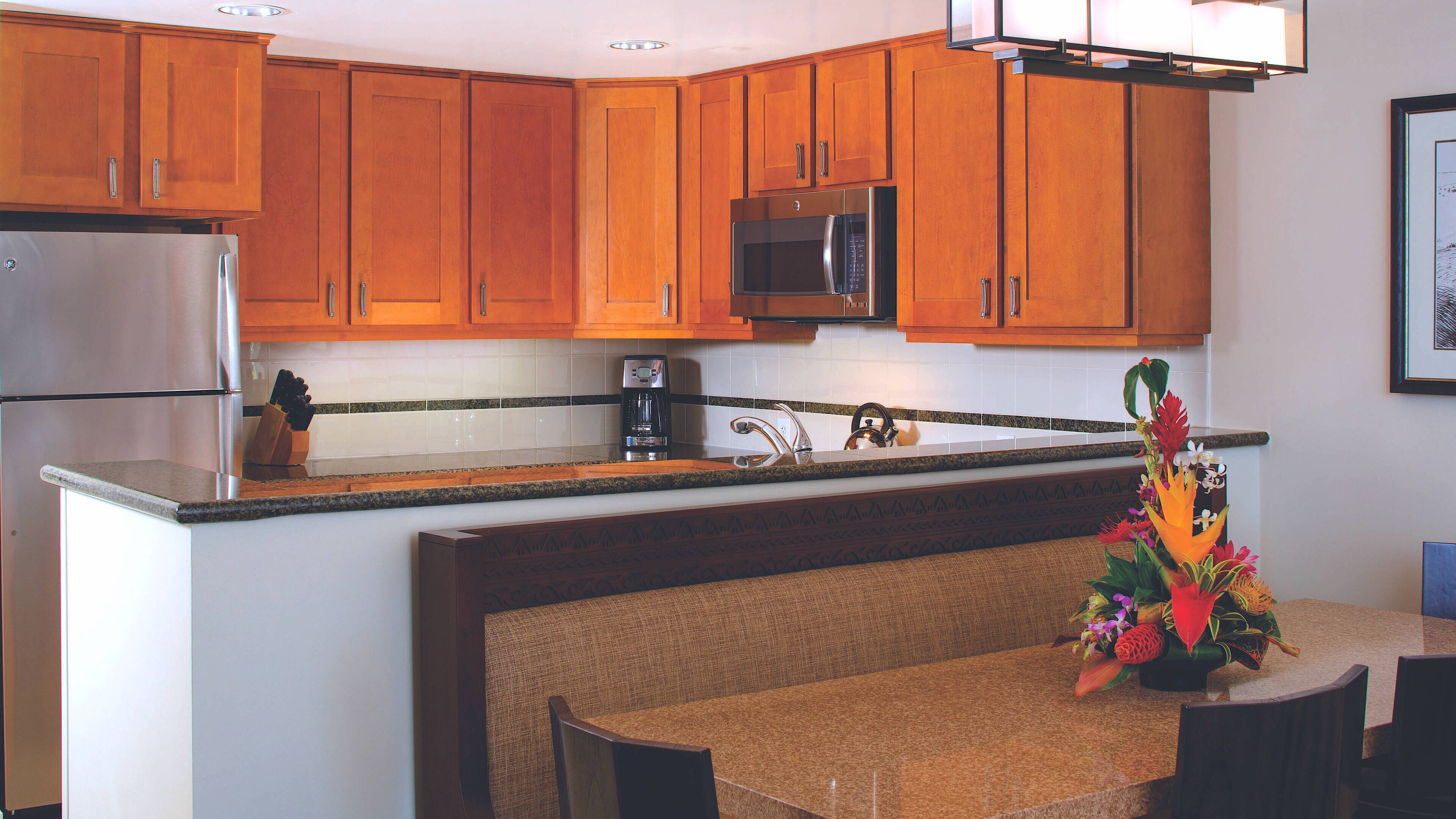 A kitchen with wooden cabinets, a stainless steel refrigerator, a microwave, and a coffee maker.