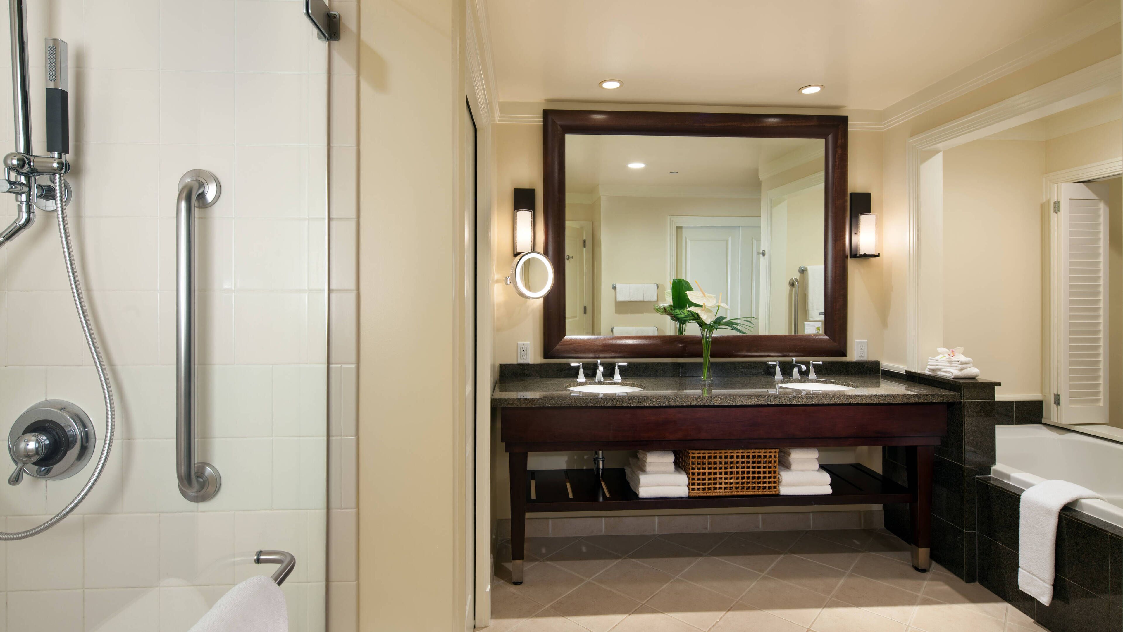 A modern bathroom with a walk-in shower, dual sinks, and a large mirror.