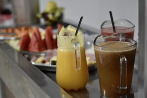 A buffet table with various food items and two drinks in glasses.