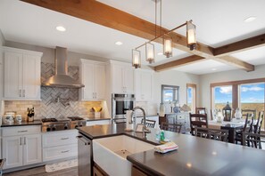 A modern kitchen with white cabinets, a stainless steel range, and a large island with a sink. - It'll Do by Silver Sands Vacation Rentals (Port Aransas)