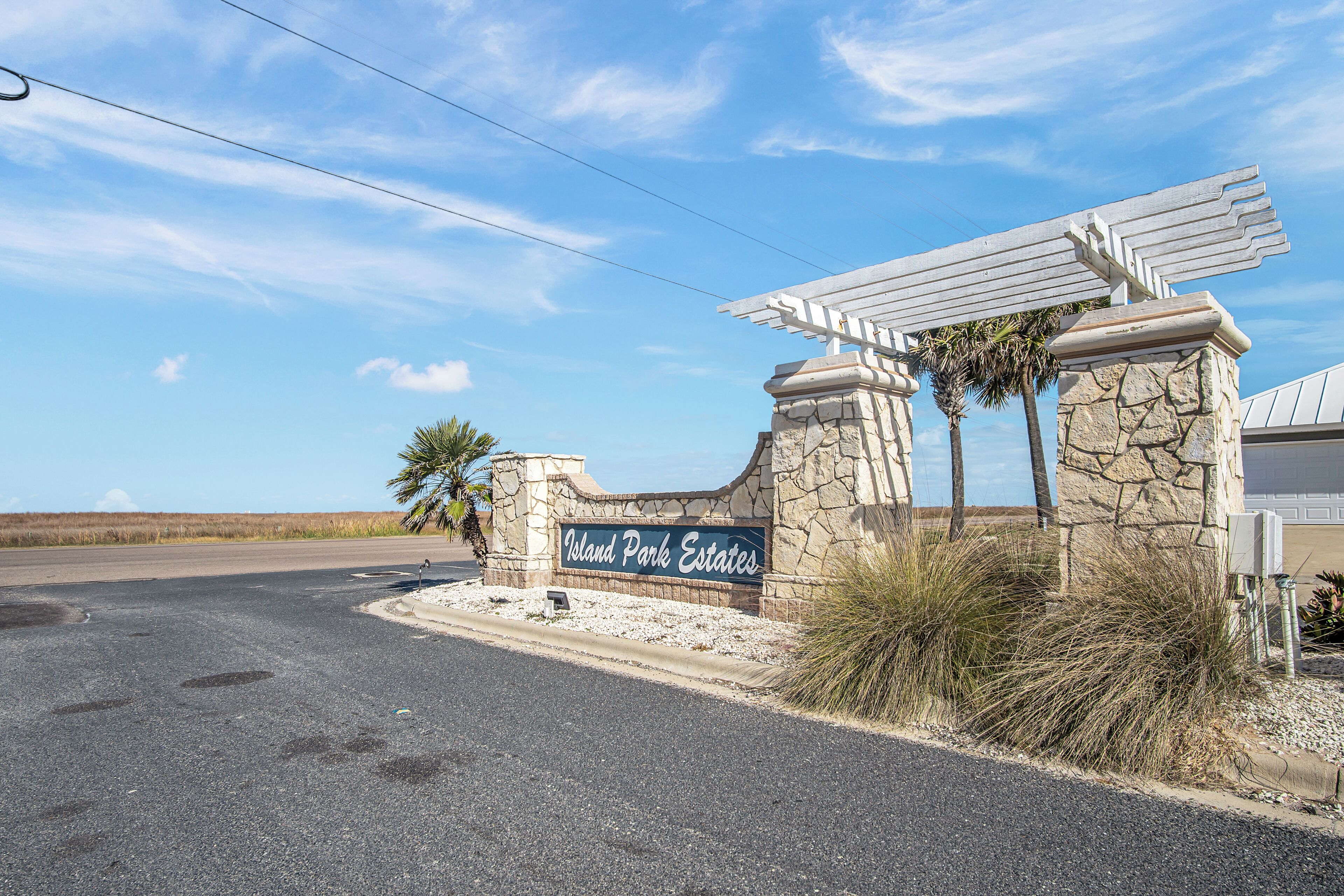A sign for Island Park Estates with a stone archway and palm trees.