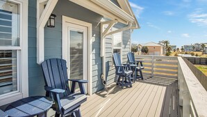 A deck with Adirondack chairs and a table, overlooking a residential area. - Downtime by Silver Sands Vacation Rentals (Port Aransas)