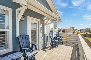 Eine Terrasse mit Adirondack-Stühlen und einem Tisch, mit Blick auf eine Wohngegend.