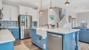 A modern kitchen with blue cabinets, stainless steel appliances, and pendant lighting. - Downtime by Silver Sands Vacation Rentals (Port Aransas)