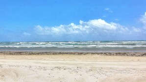 A beach with a sandy shore and waves in the background. - Downtime by Silver Sands Vacation Rentals (Port Aransas)