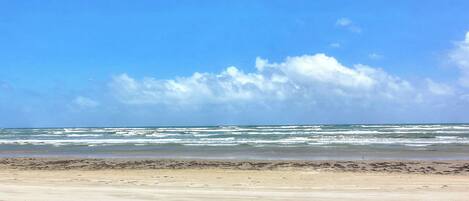 Una playa con arena y olas al fondo.