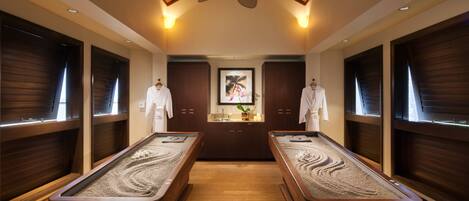 Un cuarto de spa con dos saunas, paneles de madera, un ventilador de techo y una obra de arte enmarcada en la pared.