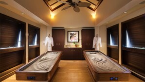 A spa room with two saunas, wooden paneling, a ceiling fan, and a framed artwork on the wall.