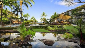 A resort with a pool, palm trees, and a small pond.