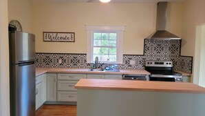 Una cocina con un refrigerador de acero inoxidable, un horno empotrado, un fregadero y una ventana.