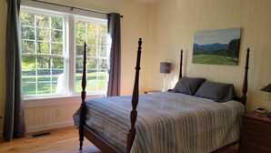 Un dormitorio con una cama con dosel, un cuadro en la pared y una ventana con cortinas.