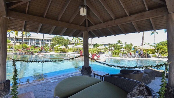 A covered pool area with lounge chairs and a view of a resort building. - 1 Bedroom - Westin Princeville Ocean Resort Villas - Full Resort Access (Princeville)