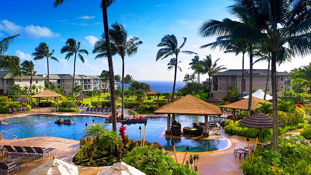 A resort with multiple swimming pools, palm trees, and a view of the ocean.