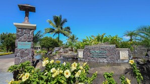 The Westin Princeville Ocean Resort Villas entrance with a stone sign, a water feature, and tropical vegetation.