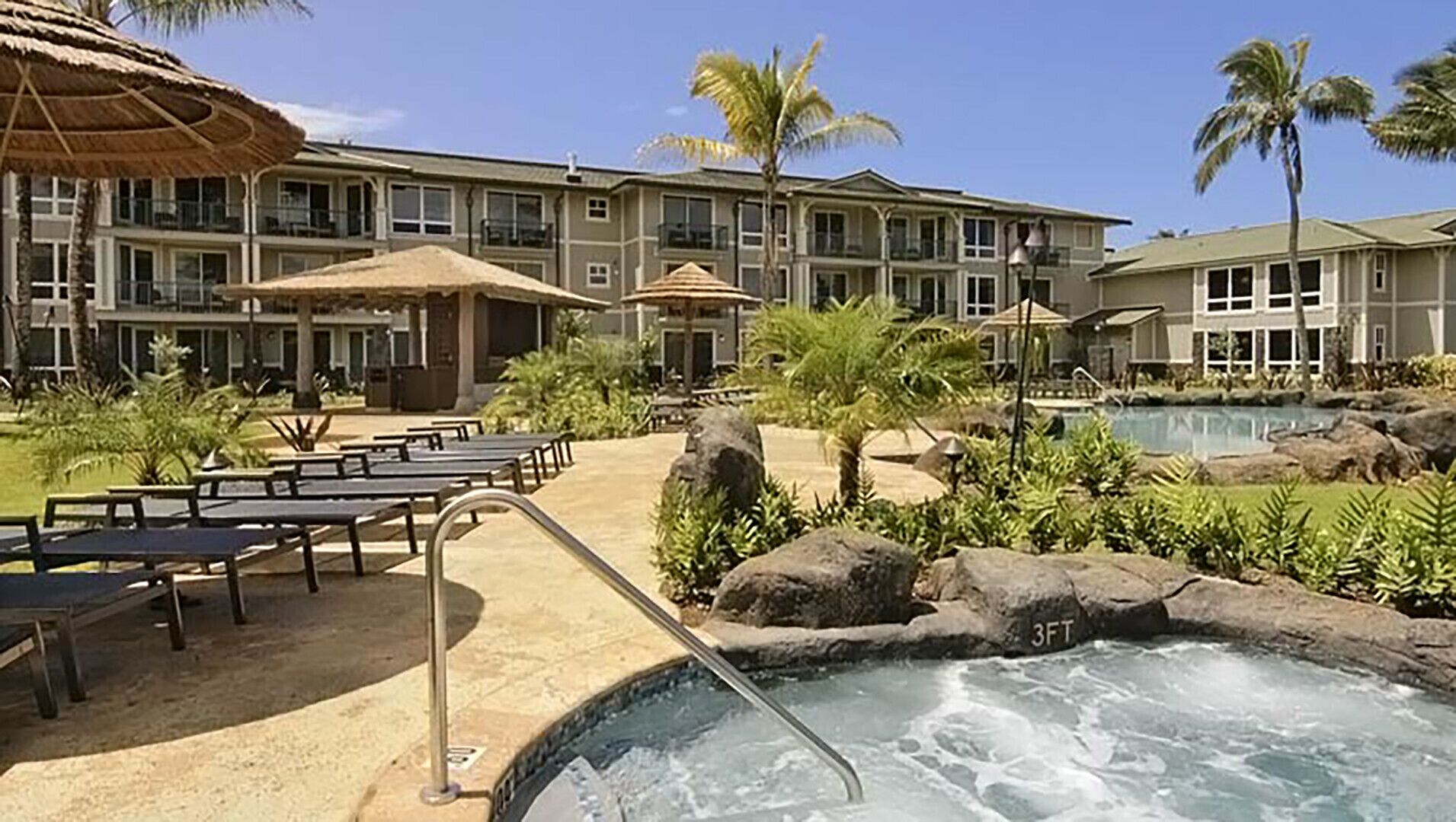 A hotel with a pool area, outdoor seating, and a building with multiple balconies.