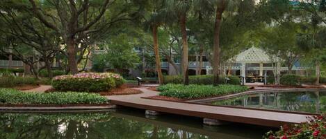 Un jardin aménagé avec un étang, des allées et un kiosque.