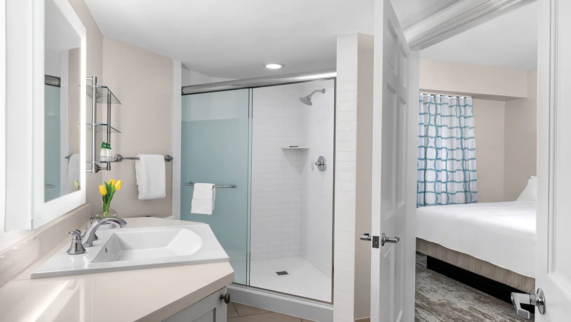 A modern bathroom with a glass-enclosed shower, a white sink, and a mirror.