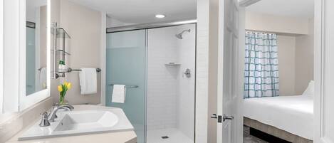 A modern bathroom with a glass-enclosed shower, a white sink, and a mirror.