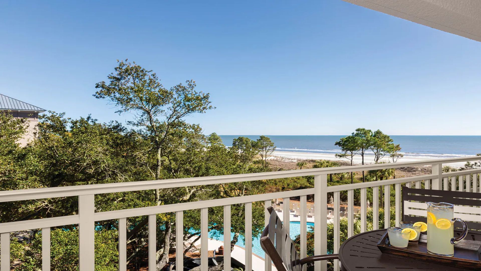 Un balcón con vista a la playa, la piscina y el océano.