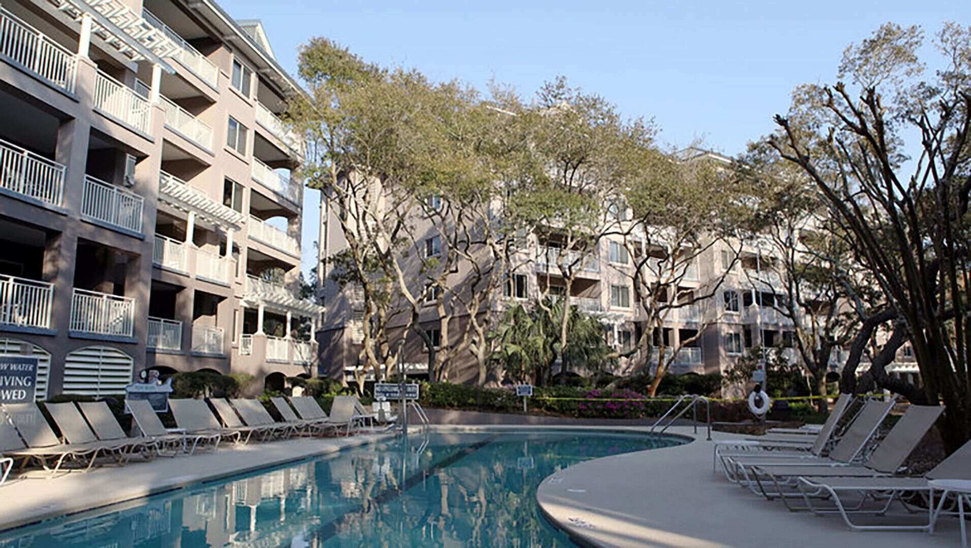 A swimming pool with lounge chairs, a water fountain, and a sign indicating 'New Water Saving'.