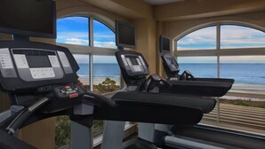 Une salle de sport équipée de deux tapis de course, dotée de grandes fenêtres et offrant une vue sur l’océan.