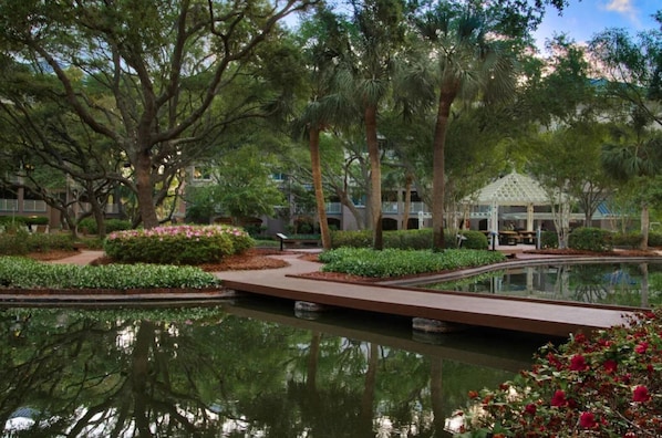 Un jardin paisible avec un étang, des allées et un kiosque.