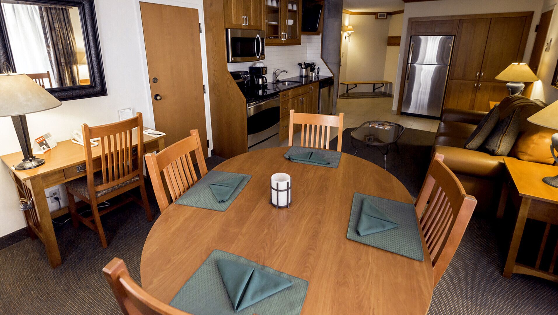 A compact hotel room with a dining area, kitchenette, and a living space.