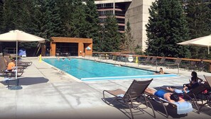 A swimming pool with lounge chairs and umbrellas, surrounded by trees and a building in the background. - 2 Bedroom - The Cliff Club at Snowbird - Full Resort Access (Snowbird)