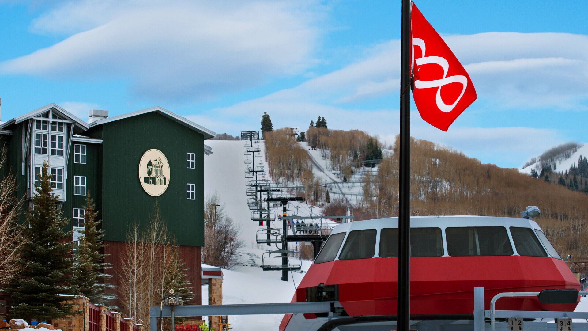A ski lift, a red bus, and a green building with a logo.