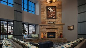 A spacious living room with a stone fireplace, large windows, and a cozy seating area.