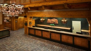A wooden interior with a reception desk, a chandelier, and a wall-mounted clock.