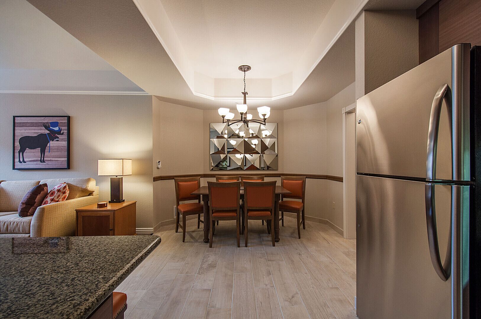 A compact living space with a dining area, a sofa, a lamp, and a refrigerator.