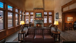 A cozy lobby with a fireplace, leather seating, and large windows offering views of a snowy landscape.