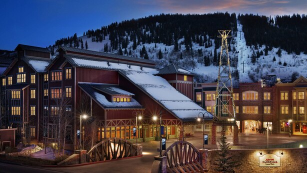 A hotel with a ski lift, snow-covered roofs, and a mountain backdrop.