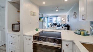 A modern kitchen with white cabinetry, a built-in oven, and a large island with a microwave.