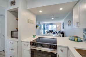 A kitchen with white cabinetry, a built-in oven, and a stove. - 35 Steps to the Beach at Runaway Bay 104 (Bradenton Beach)