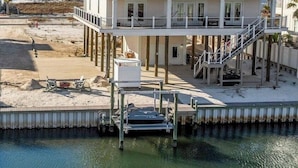 Ein Strandhaus mit zwei Etagen, einem Balkon, einem Steg und einem Swimmingpool.
