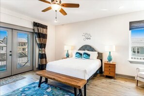 A bedroom with a bed, bedside tables, a ceiling fan, and a window with curtains.