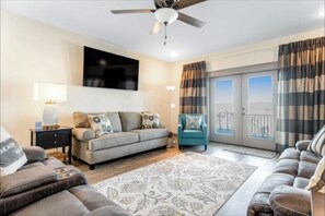Relax in this stylish living room with a flat-screen TV, comfortable seating area, and sliding glass door leading to a city view.